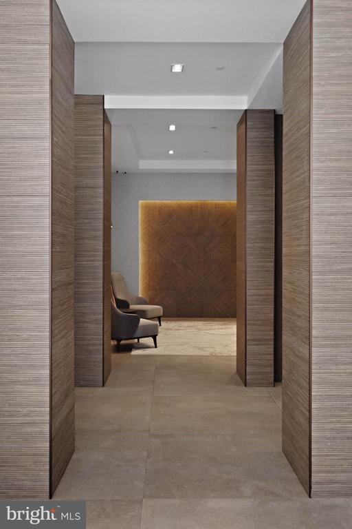 Hallway with textured wood walls, lounge chairs, and a backlit wood feature wall.