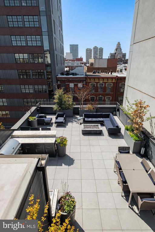 Rooftop terrace with outdoor seating, planters, and a Philadelphia city skyline view.