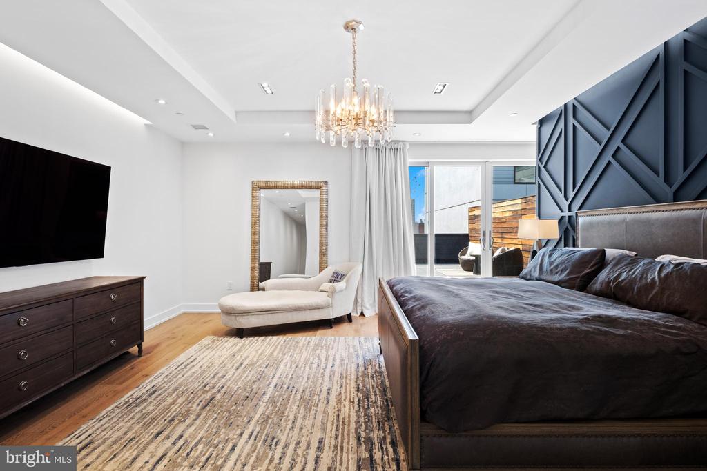 Contemporary bedroom with a dark bed, geometric navy accent wall, and glass doors to a terrace.