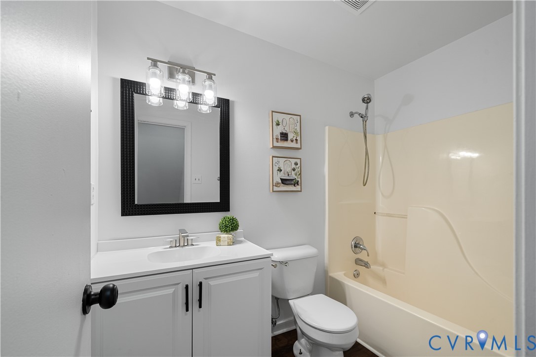 Bathroom with a white vanity, black-framed mirror, and cream tub-shower surround.