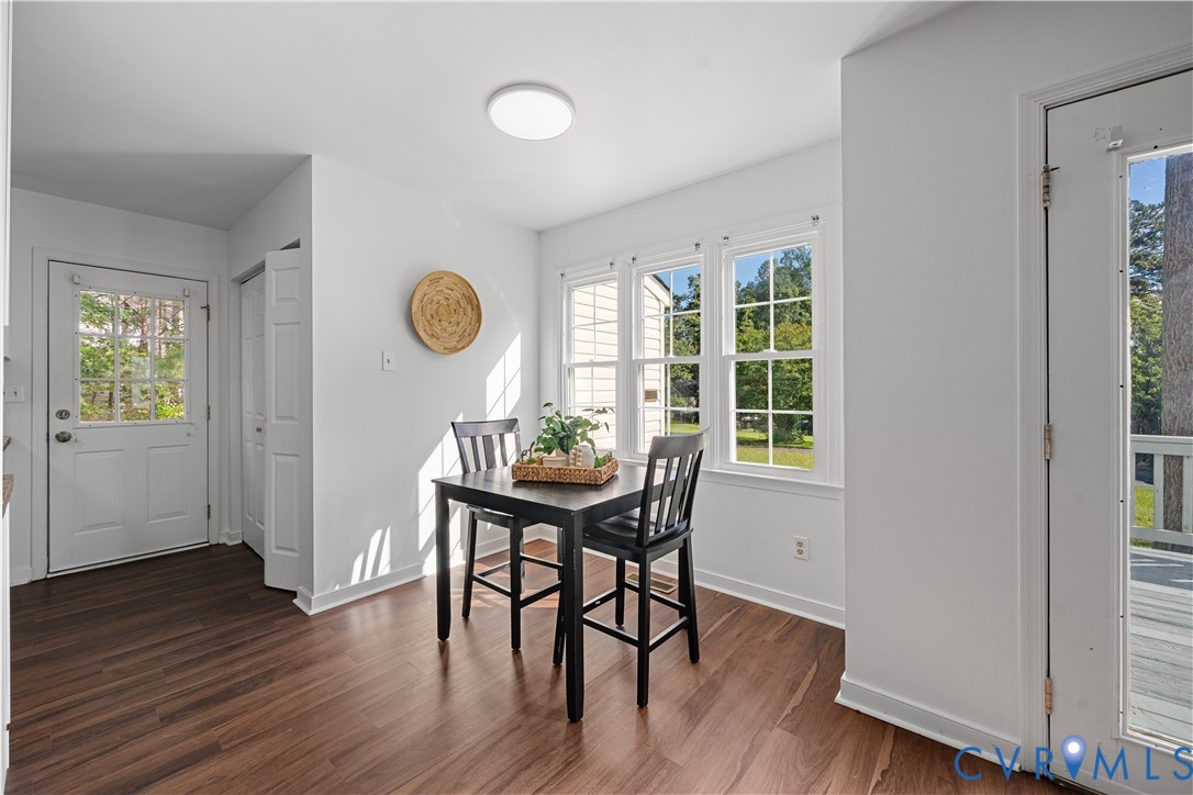 Bright dining nook with a black table and chairs beside large windows overlooking the yard.