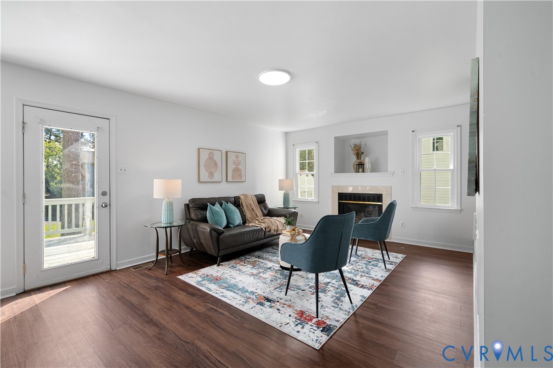 Furnished living room with a gray sofa, teal chairs, patterned rug, and fireplace.