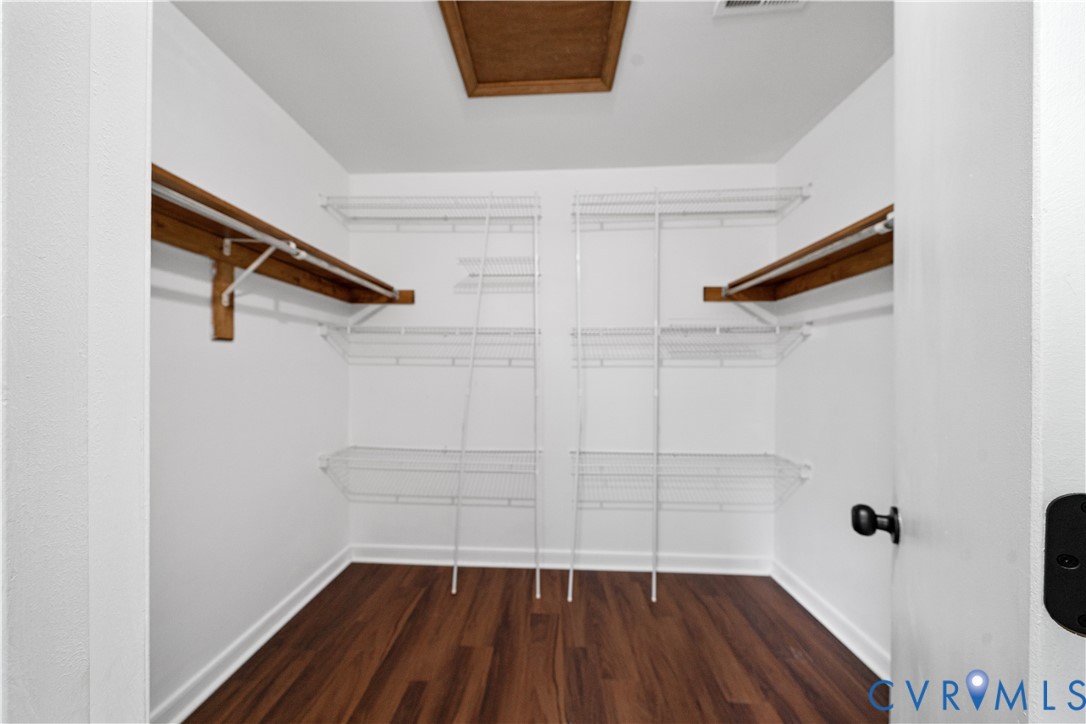Walk-in closet with white wire shelving, wooden side shelves, and dark wood flooring.