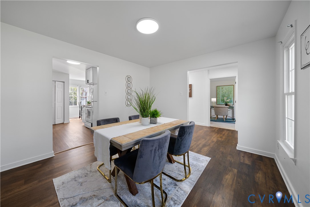 Staged dining room with a wood table and upholstered chairs, opening to the kitchen and sitting room.