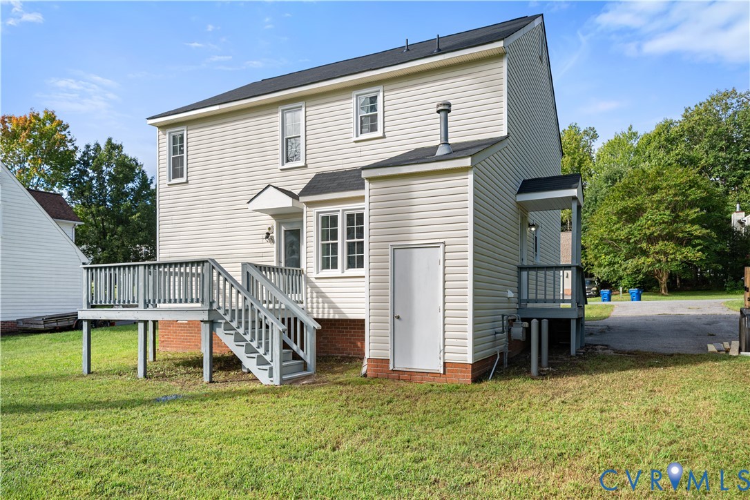 Two-story house with a raised gray deck and stairs, small covered side porch, and broad lawn.
