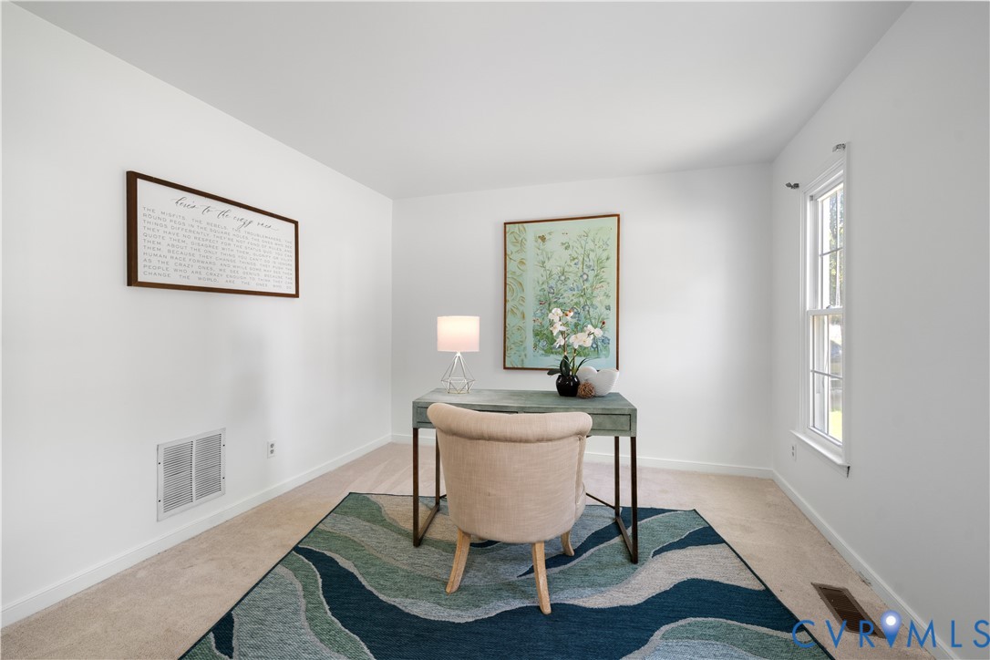 Staged home office with a green desk, upholstered chair, and blue-and-green patterned rug.