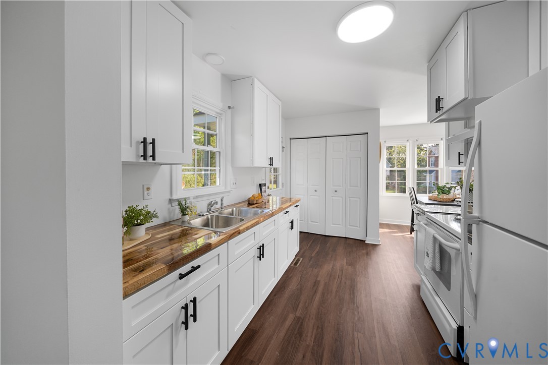 Galley kitchen with white cabinets, butcher-block countertops, and a double-basin sink.