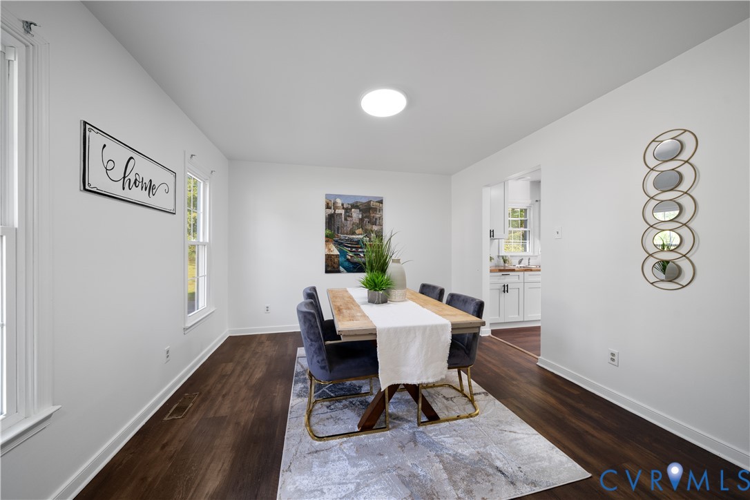 Dining room with a wooden table, upholstered chairs, and a doorway to the kitchen.