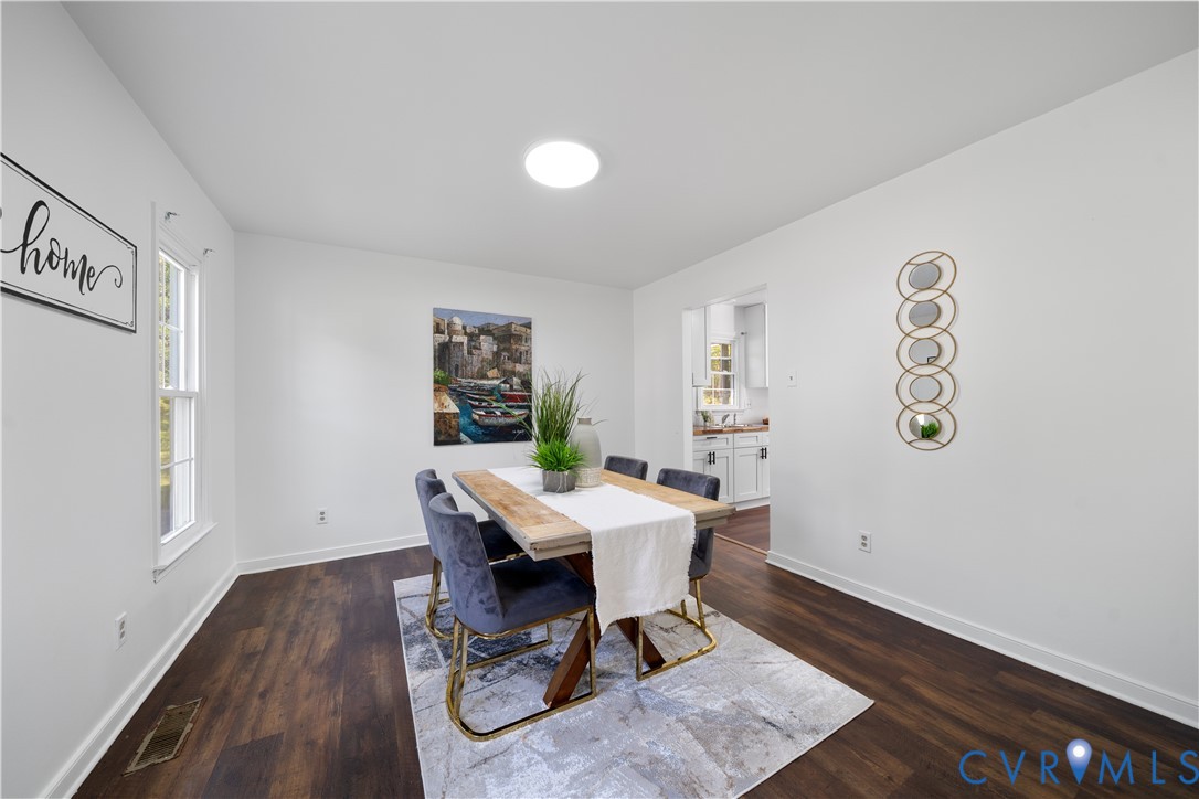 Staged dining room with a wood table, blue chairs, and a doorway opening to the kitchen.