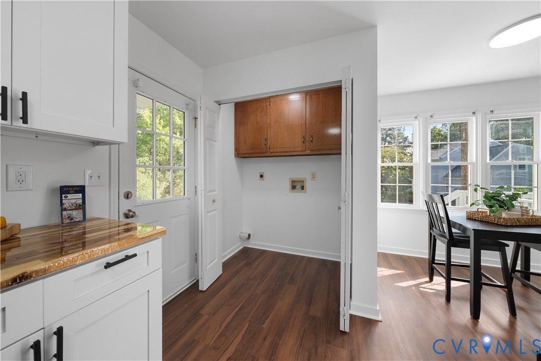Kitchen with a wood countertop, white cabinetry, and an adjoining dining area.