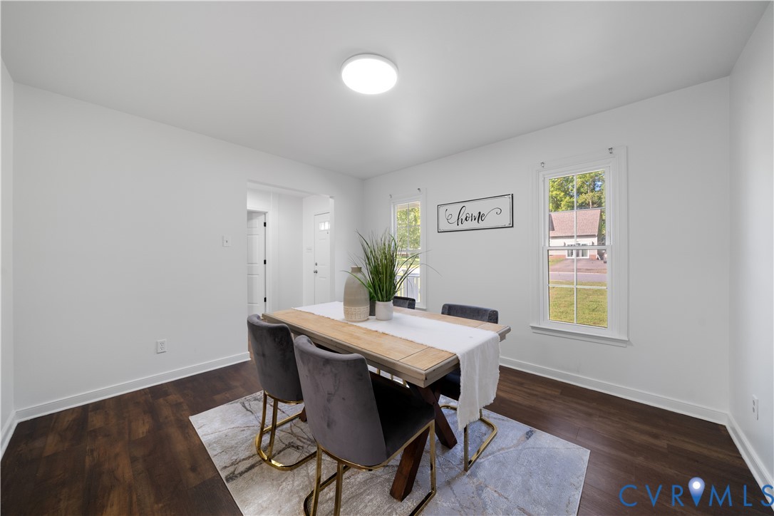 Staged dining room with a light wood table, dark chairs, and windows overlooking a lawn.