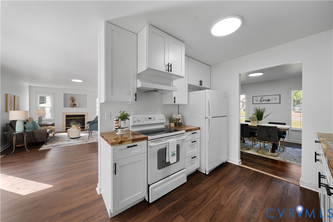 Kitchen with white cabinets, butcher-block counters, stainless appliances, and open connections to living and dining areas.