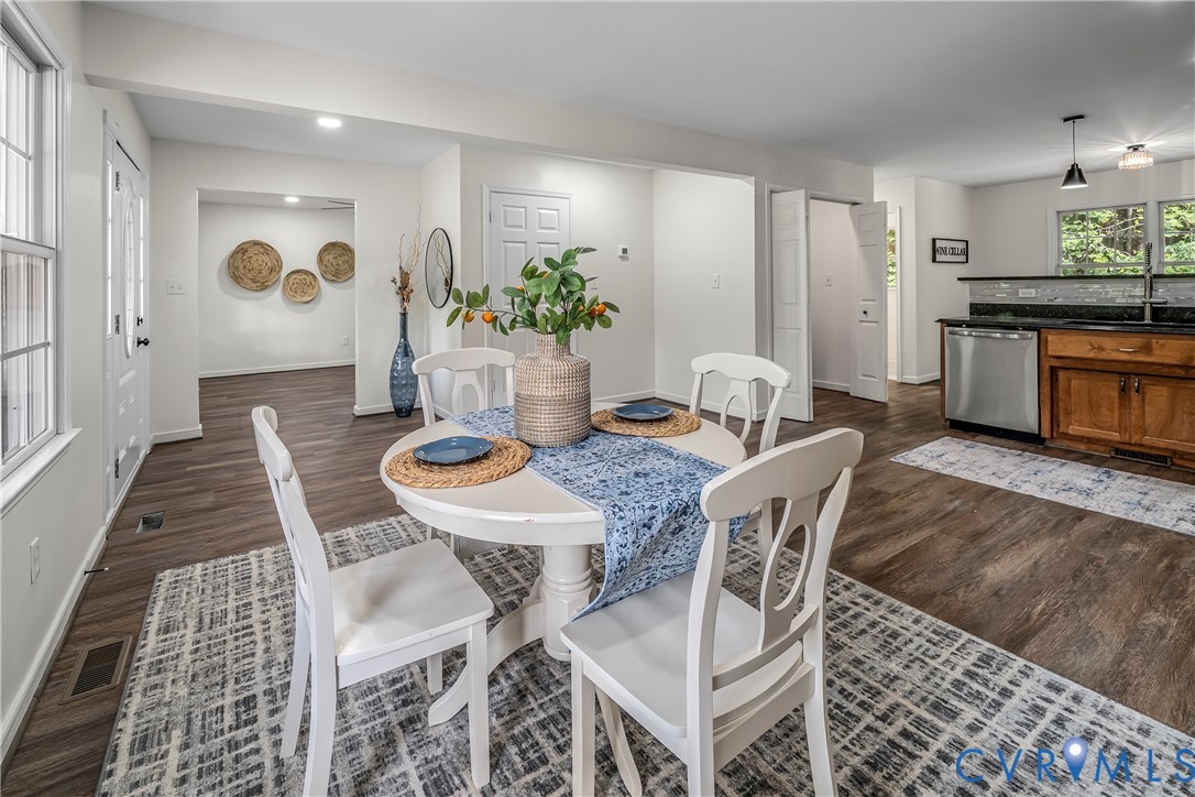Dining area with a round white table and blue runner beside an open kitchen.