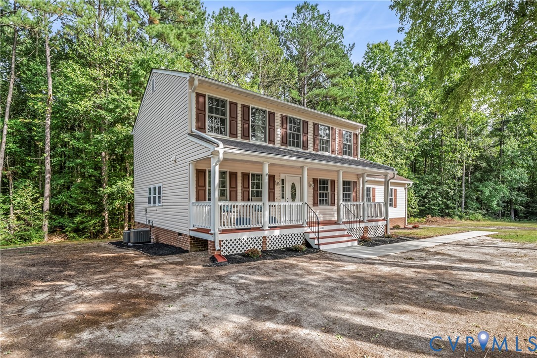 Two-story house with a covered front porch and broad driveway, surrounded by mature trees.