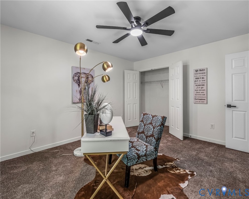 Furnished home office with a white desk, patterned chair, and open closet.