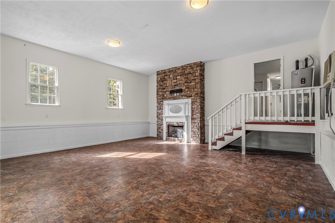 Empty room with a stone fireplace, brown tile floor, and raised area reached by a short staircase.