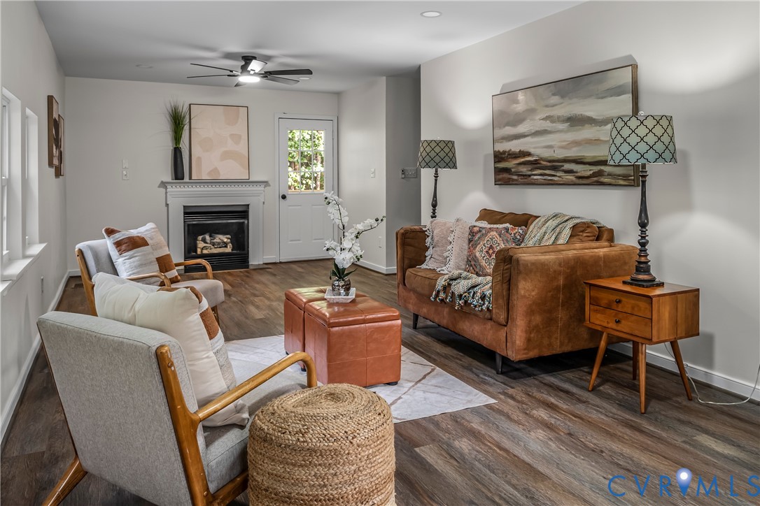 Staged living room with a fireplace and brown leather sofa beside gray armchairs.