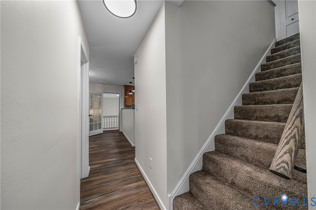 Hallway with dark wood-look flooring and a carpeted staircase beside it.