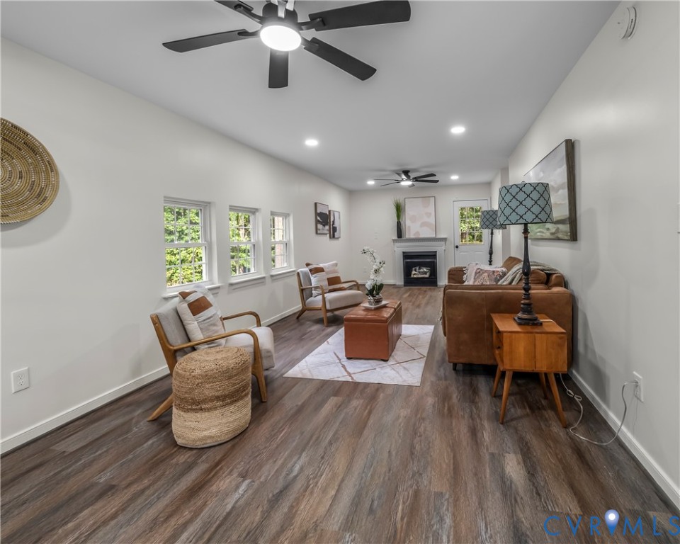 Living room with leather seating, a fireplace, and wood-look floors.