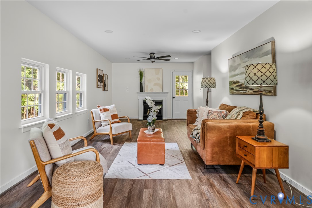 Staged living room with a fireplace, three tall windows, and caramel-colored seating.