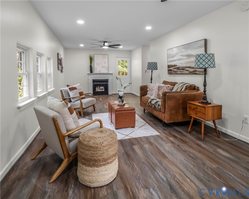 Staged living room with a brown sofa, fireplace, and large windows.