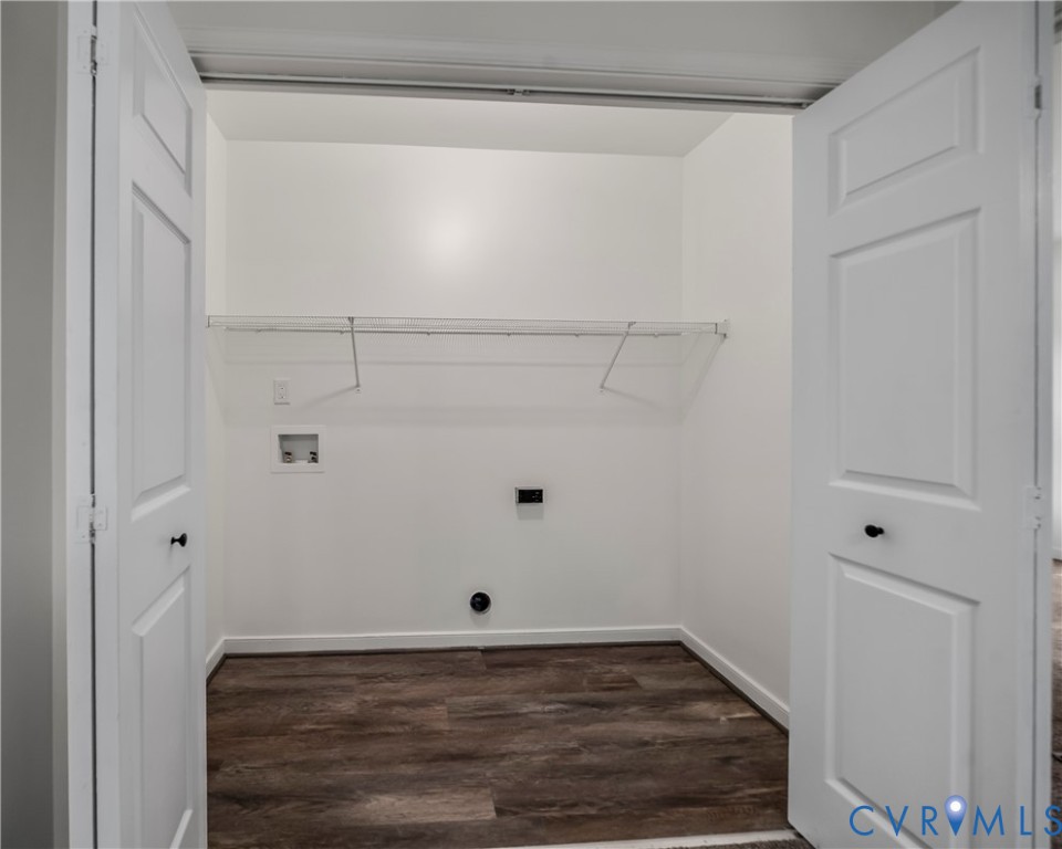 Empty laundry room with washer and dryer hookups, a wire shelf, and dark wood-look flooring.