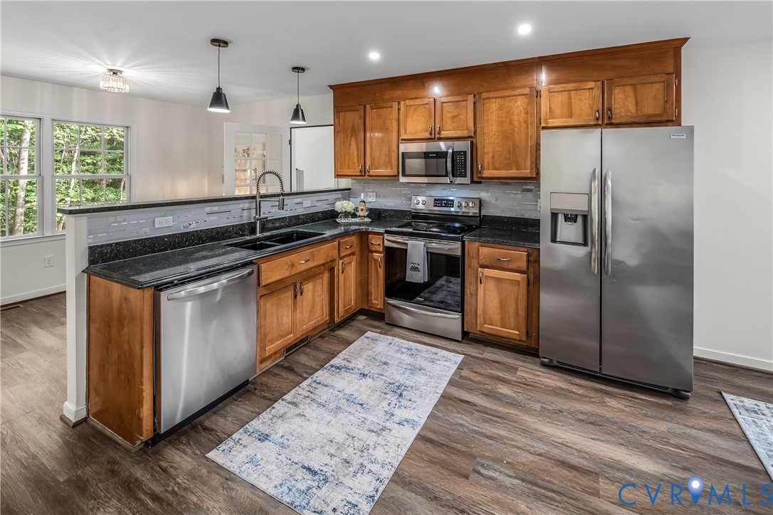 Kitchen with warm wood cabinets, dark countertops, and stainless steel appliances.