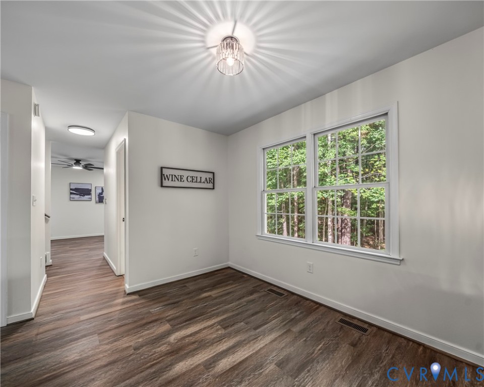 Empty wine cellar room with wood-look flooring and a large window overlooking trees.