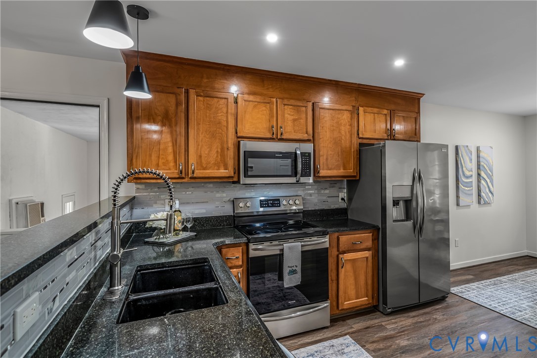 Kitchen with warm wood cabinets, black granite counters, and stainless steel appliances.