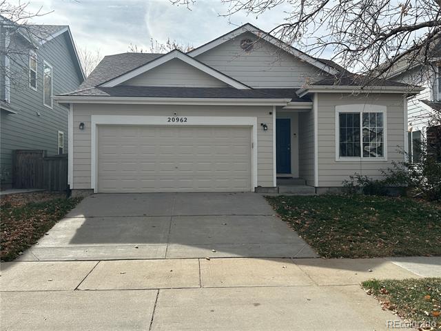 Gray-sided house with a two-car garage, blue front door, and wide concrete driveway.