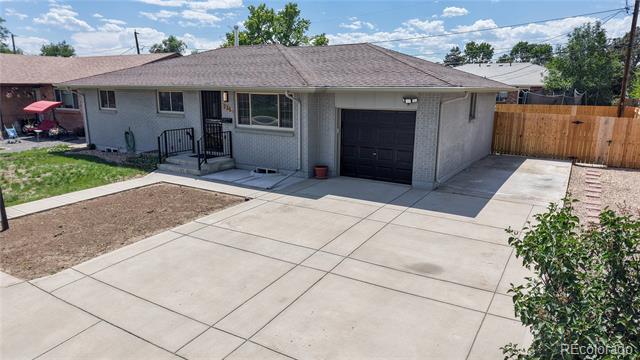Gray single-story home with an attached garage, front porch, and broad concrete driveway.