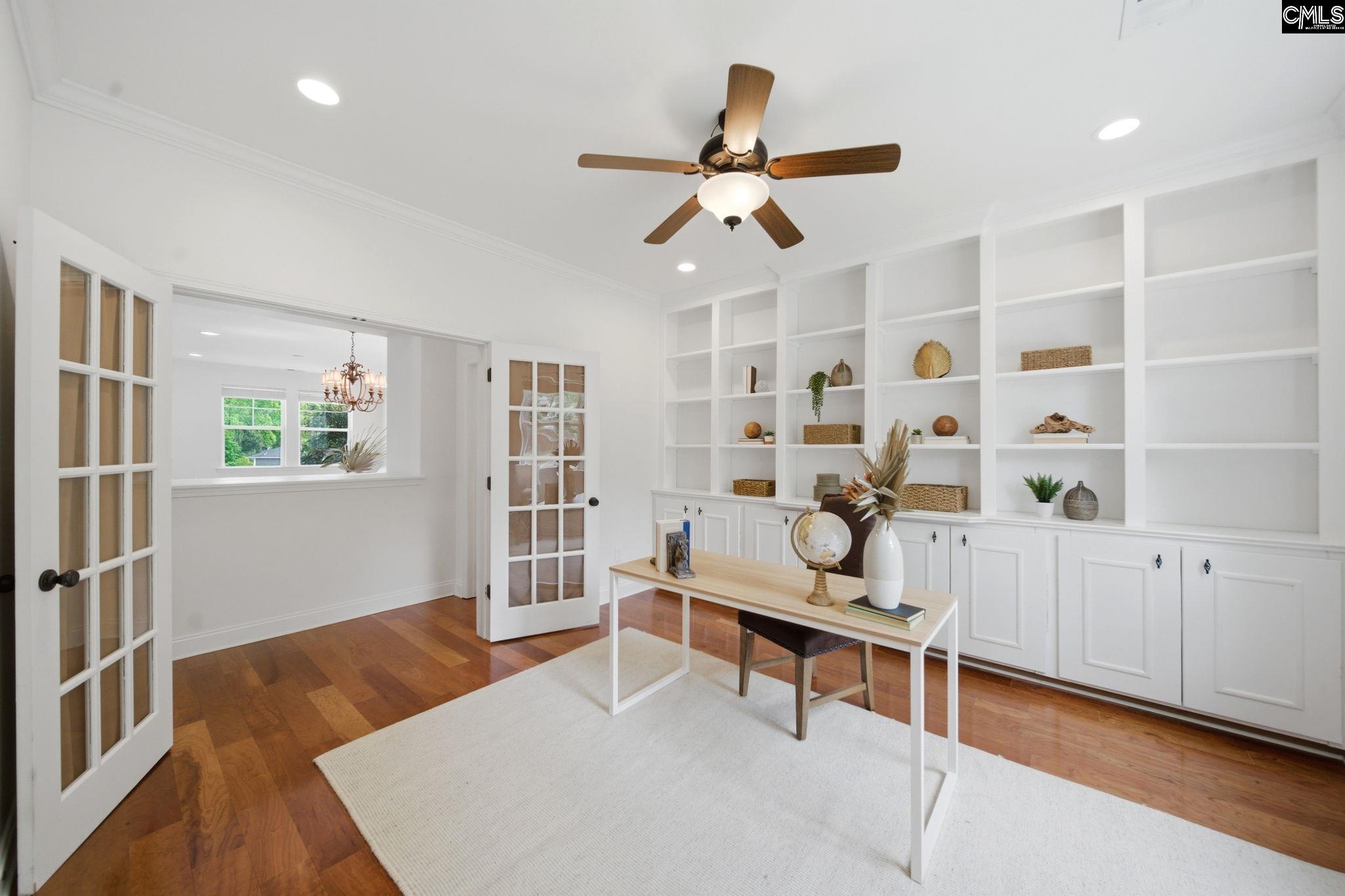 Home office with built-in white shelving, French doors, and a desk on a light rug.