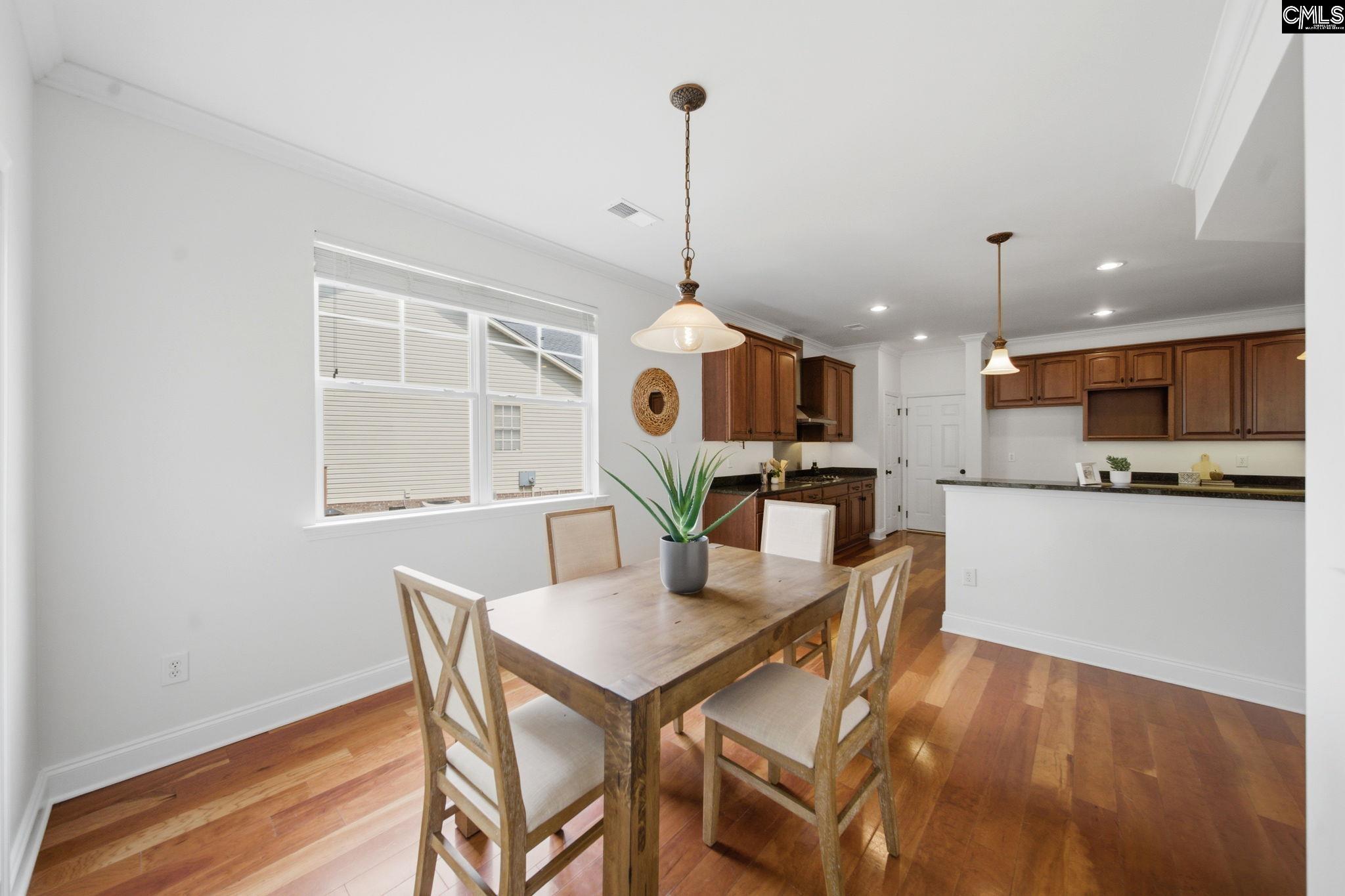 Kitchen and dining area with a wood table, hardwood floors, and dark wood cabinets.