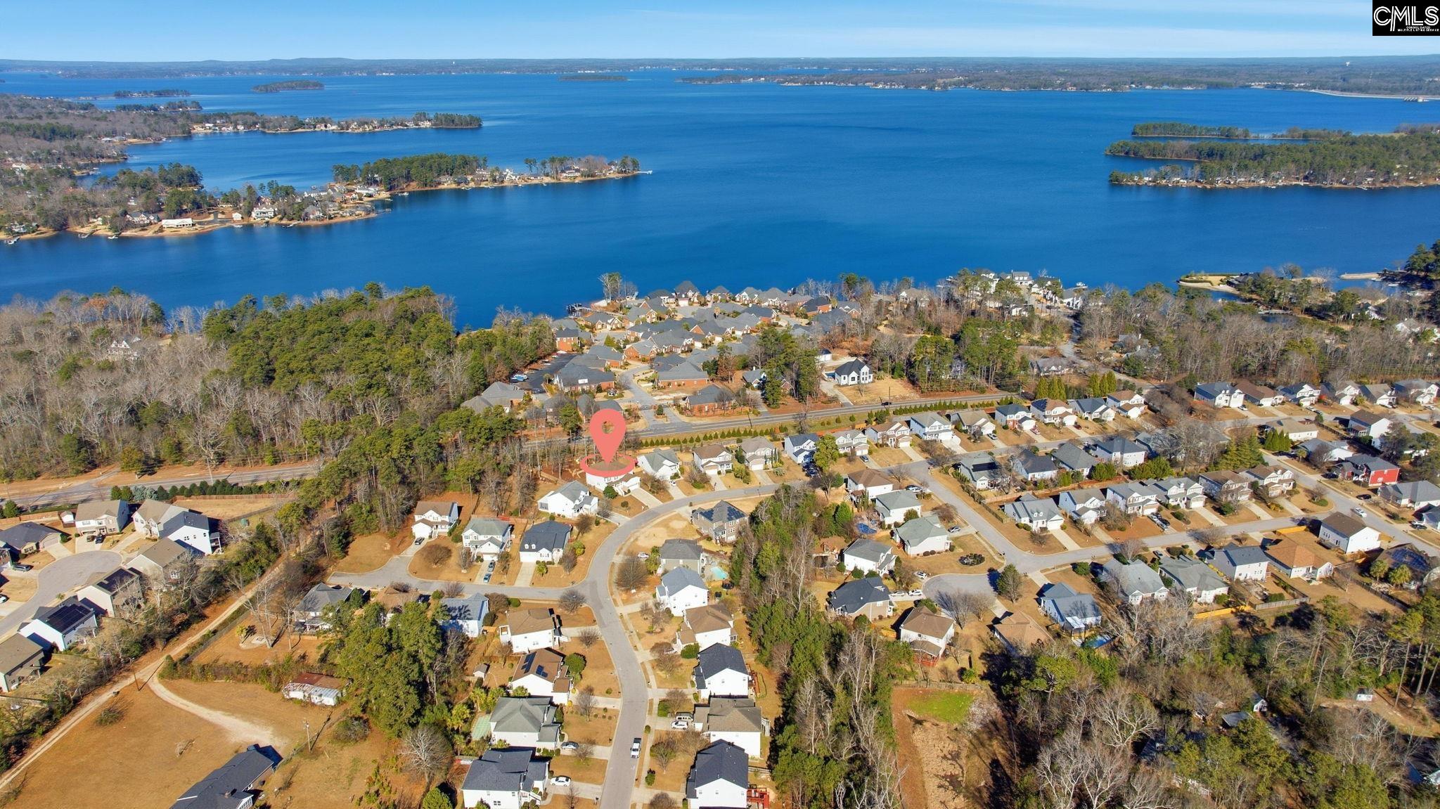 Aerial panorama of a lakeside neighborhood, with a map pin marking a home near the water.