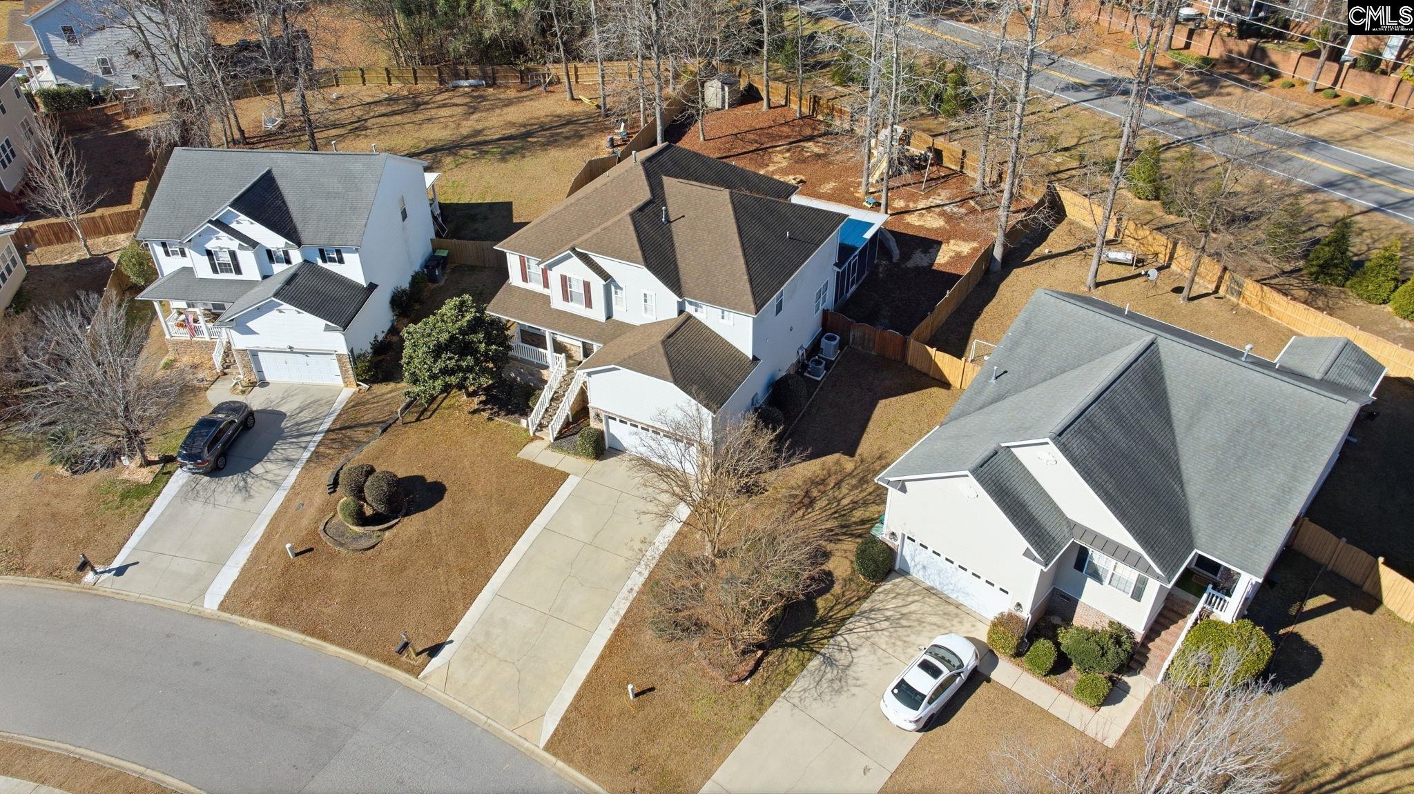 Aerial view of a two-story home with a fenced backyard and neighboring houses.