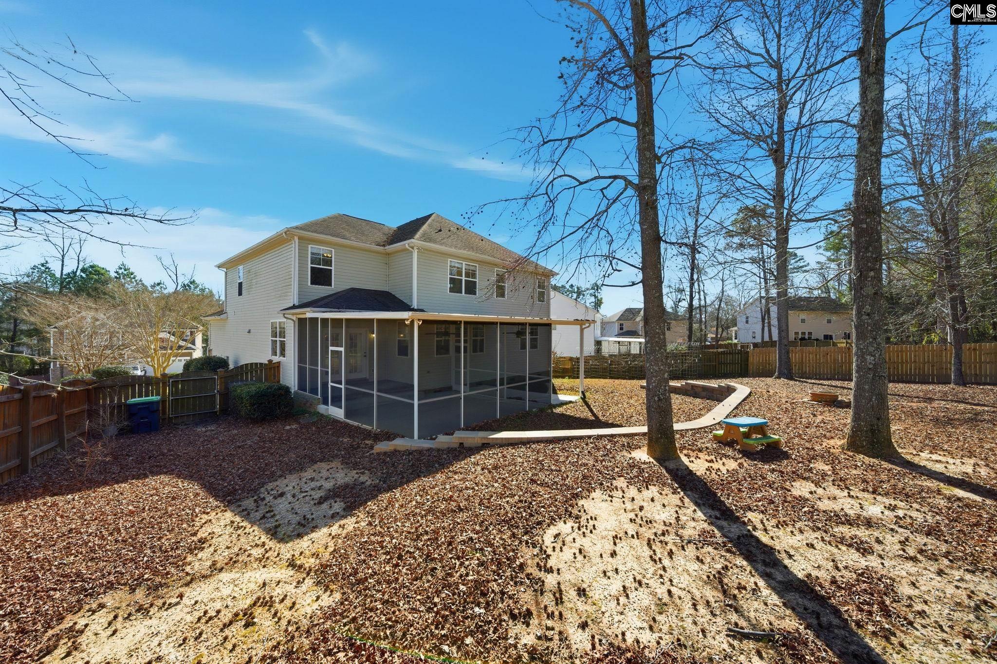 Two-story home with a screened porch overlooking a fenced, leaf-covered backyard.
