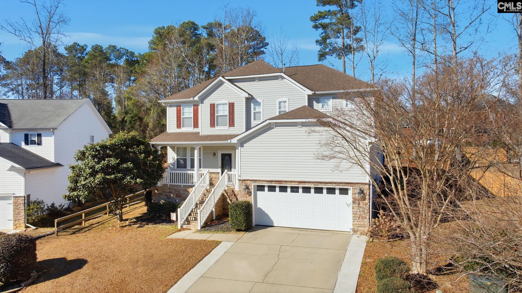 Two-story gray house with red shutters, covered porch, stone accents, and attached garage.