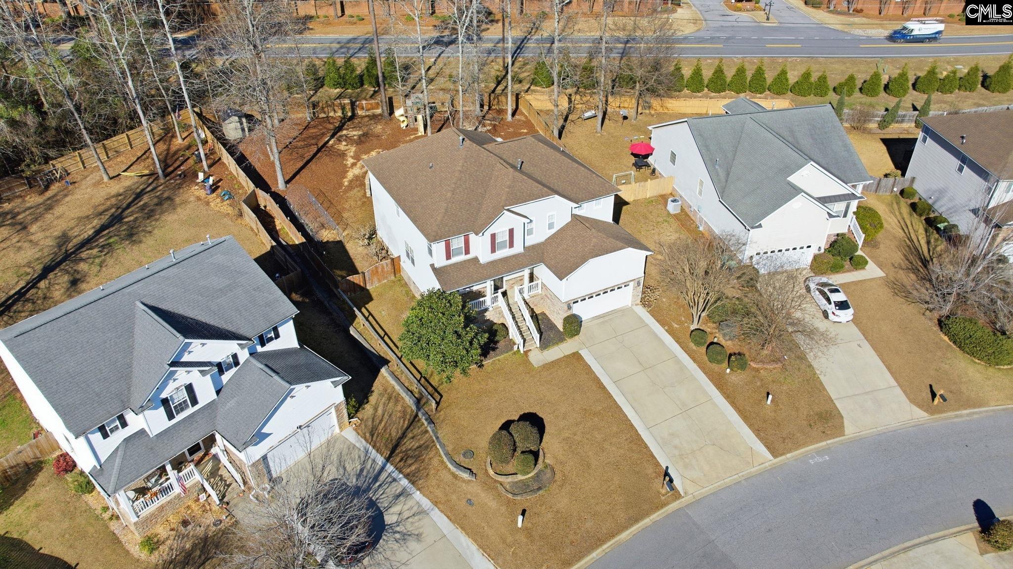 Aerial view of a white two-story home with a fenced backyard and driveway.