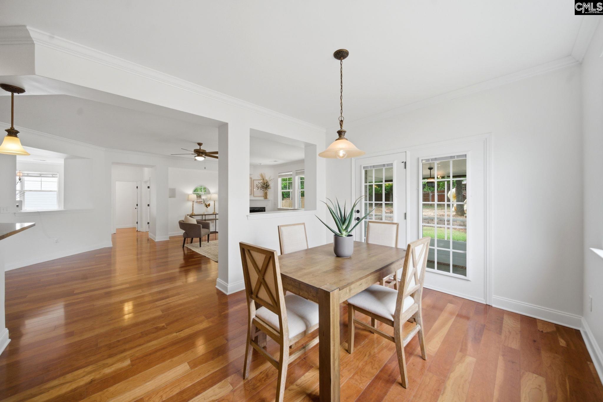 Dining area with a wooden table, hardwood floors, and French doors opening to the yard.