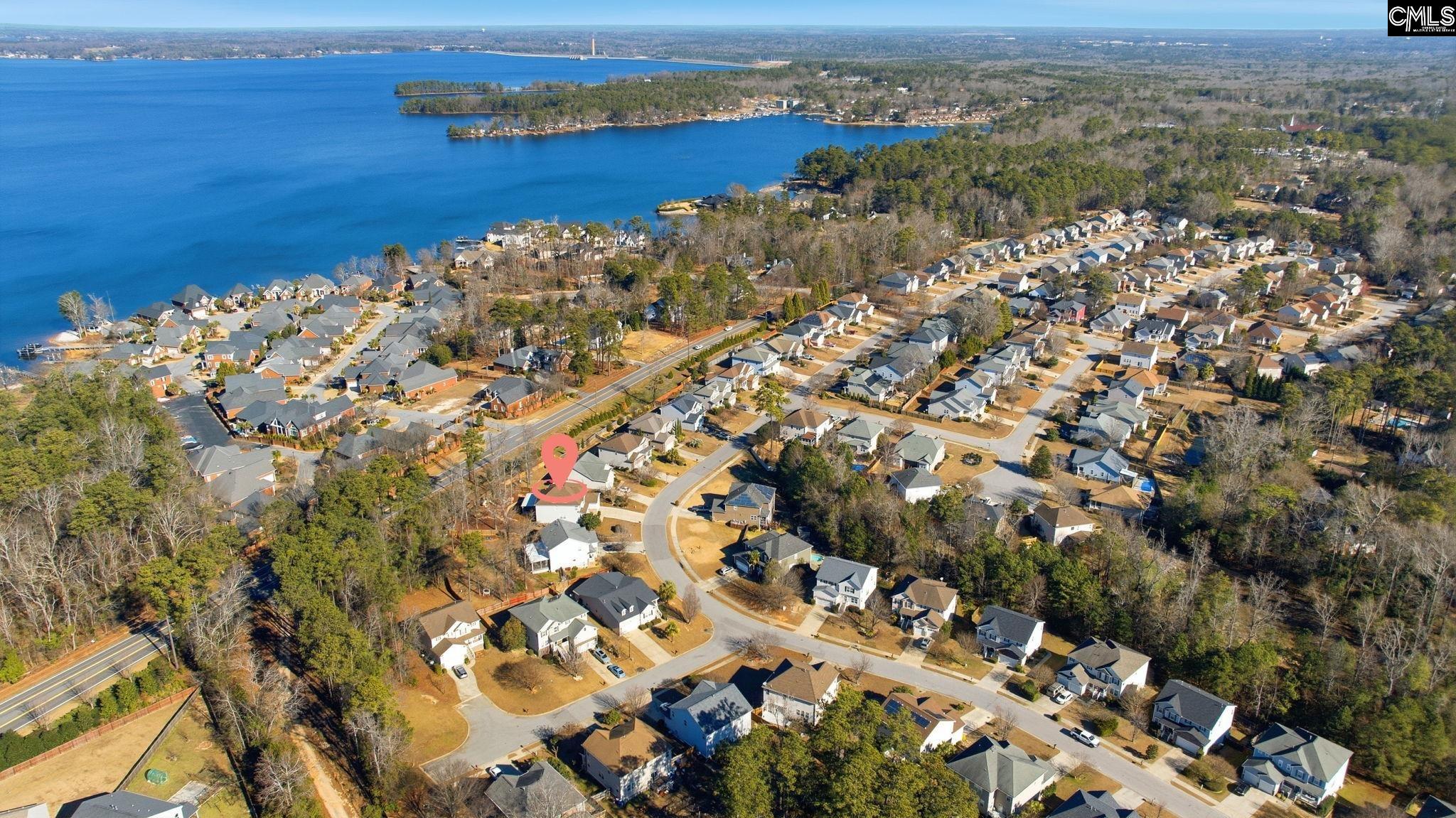 Aerial view of a lakeside neighborhood, with the featured home marked among the houses.