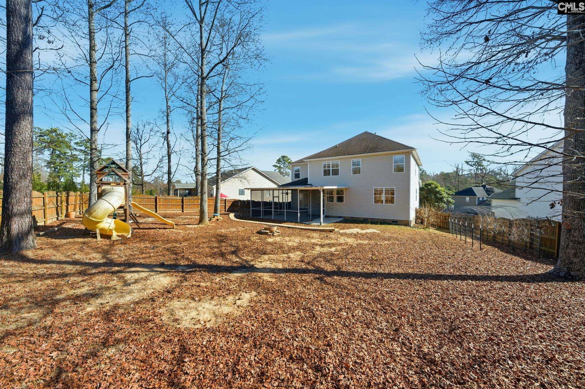 Two-story home with a screened porch, fenced leaf-covered backyard, and children’s playset.
