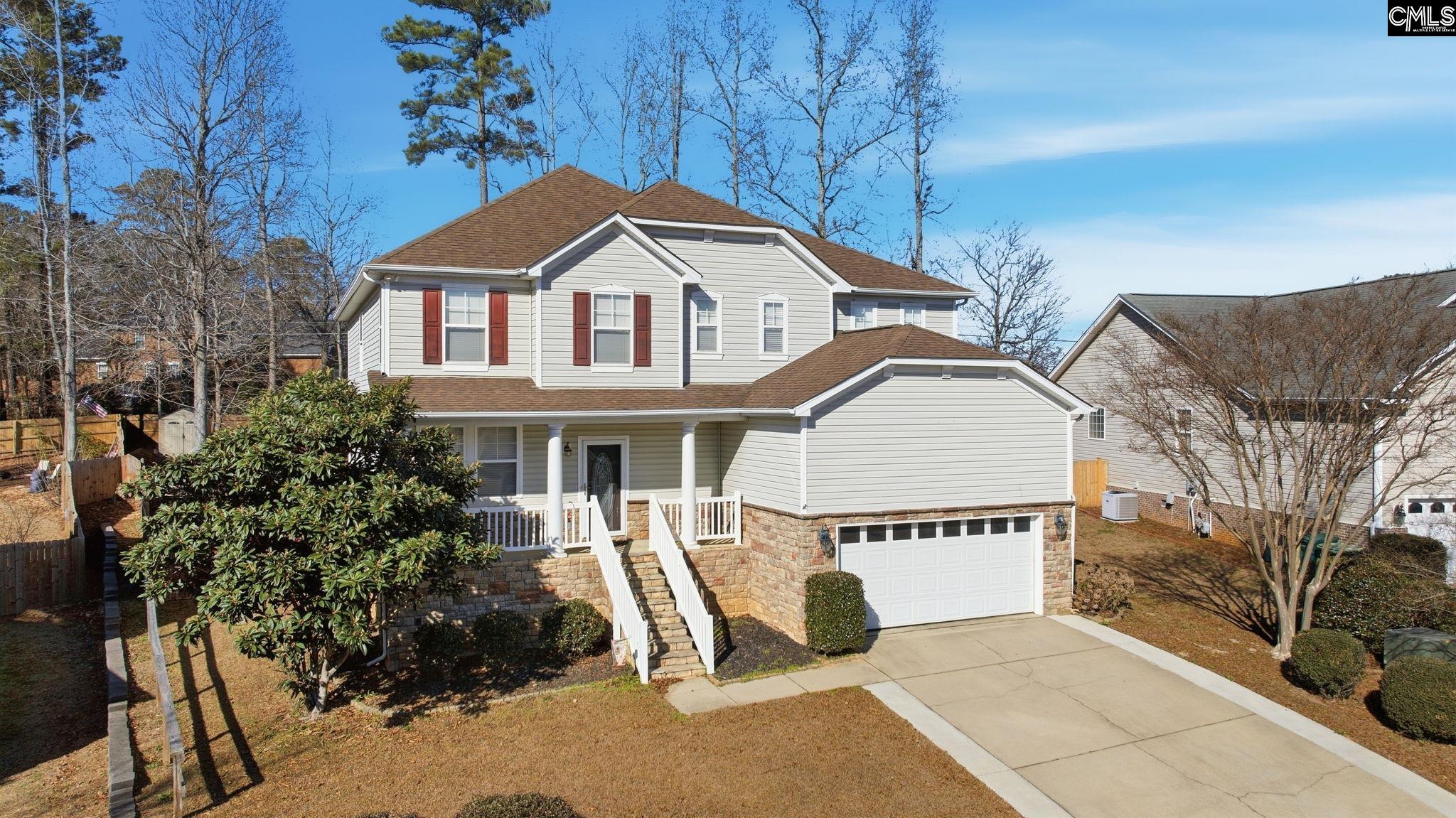 Two-story gray home with red shutters, stone lower level, front porch, and attached garage.