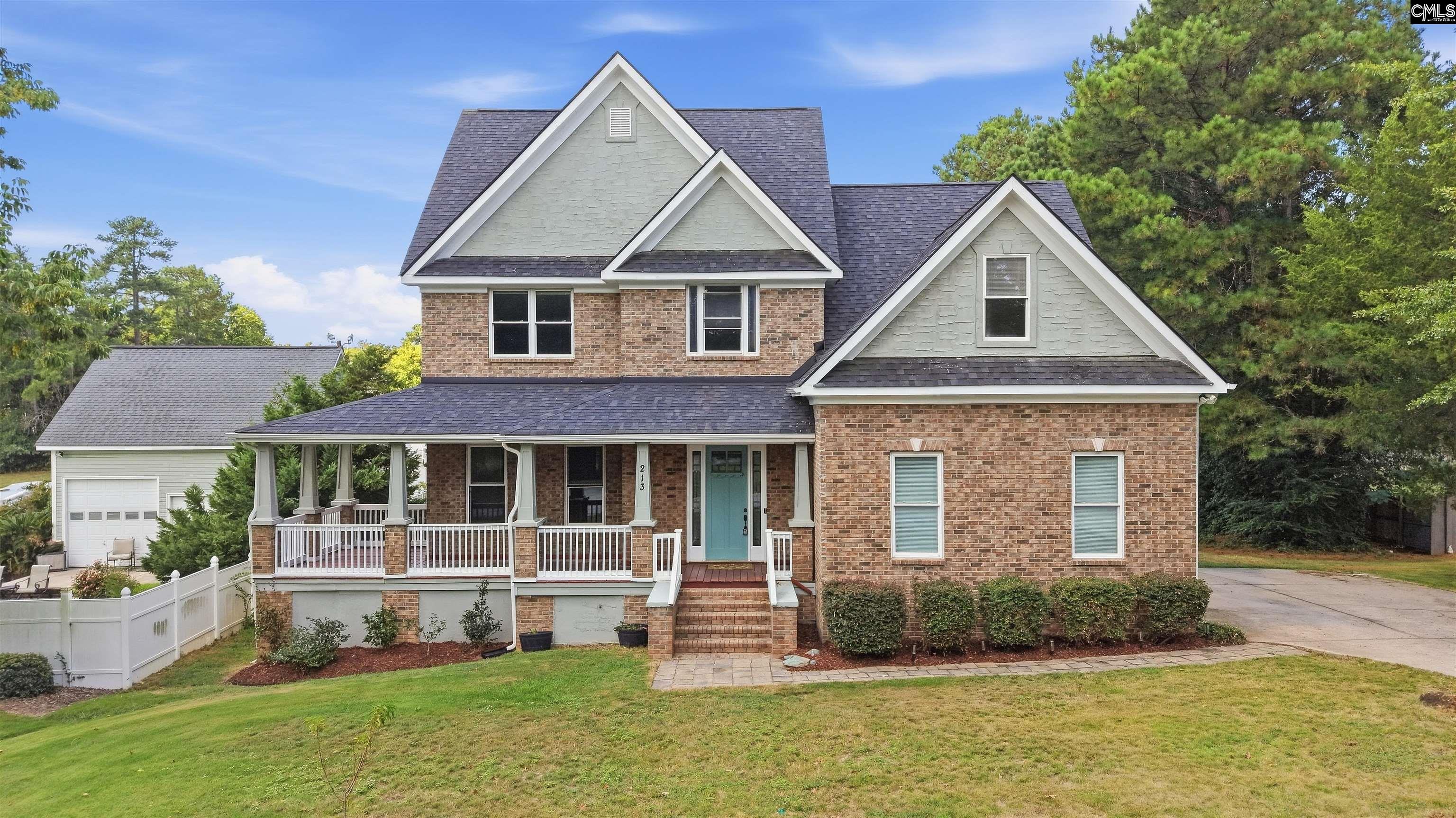 Two-story brick house at 213 Headwater Circle with a covered porch, teal door, and attached garage.