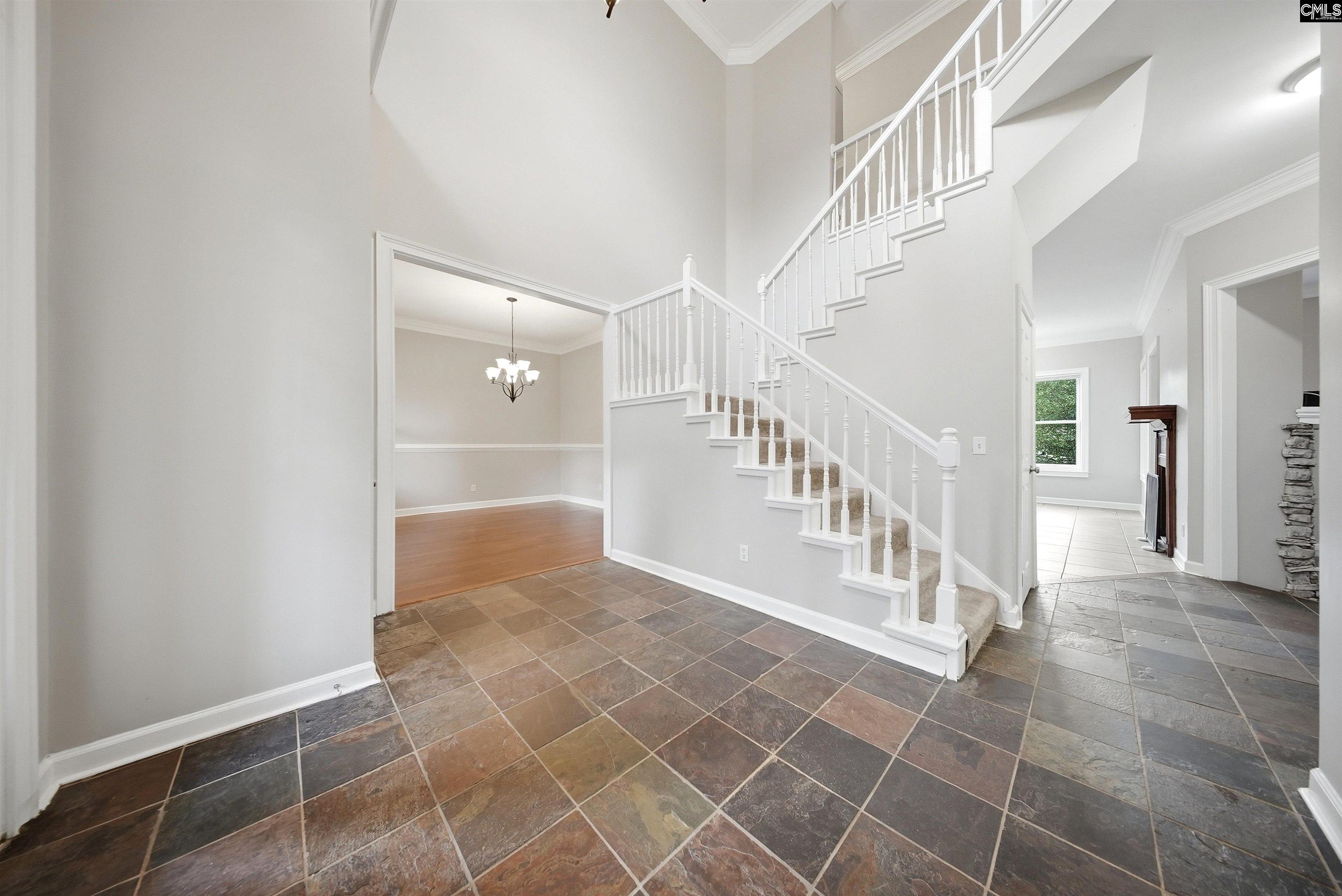 Foyer with stone tile floors, a white staircase, and open doorways to adjoining rooms.