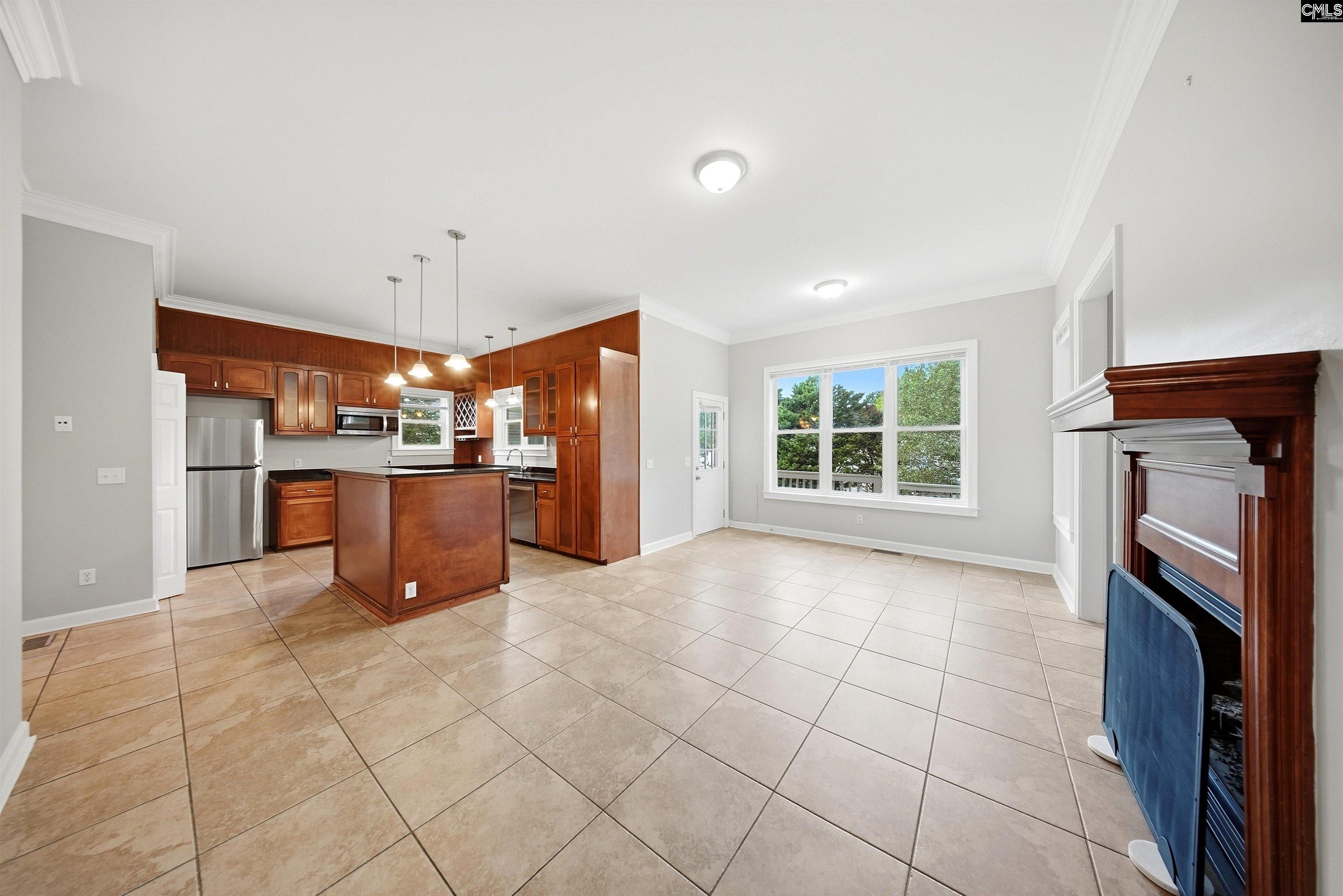 Kitchen and dining area with a wood-cabinet island, tile floors, large window, and fireplace.