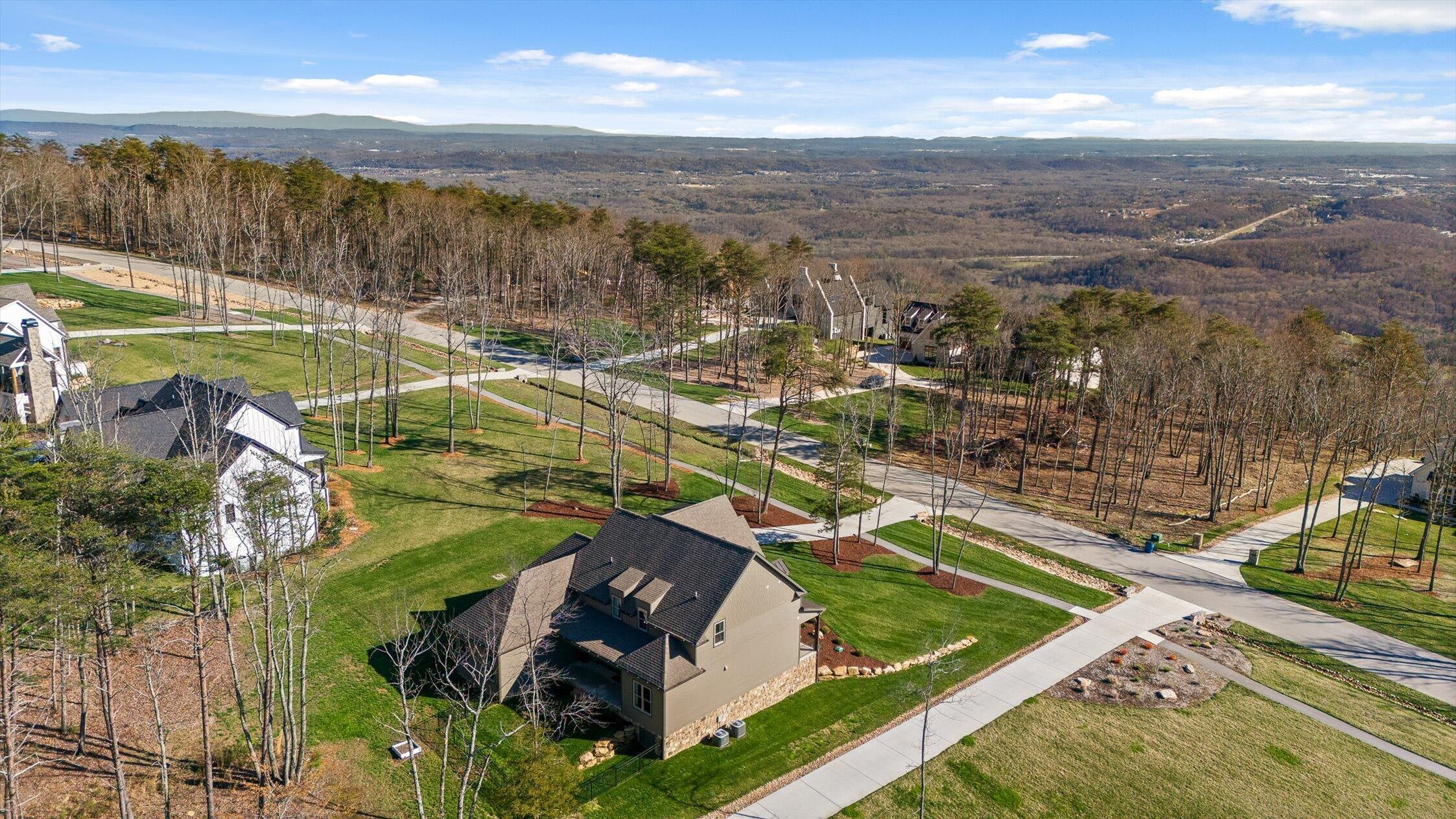 Aerial view of a home among wooded lots, with a broad valley and distant ridgelines beyond.