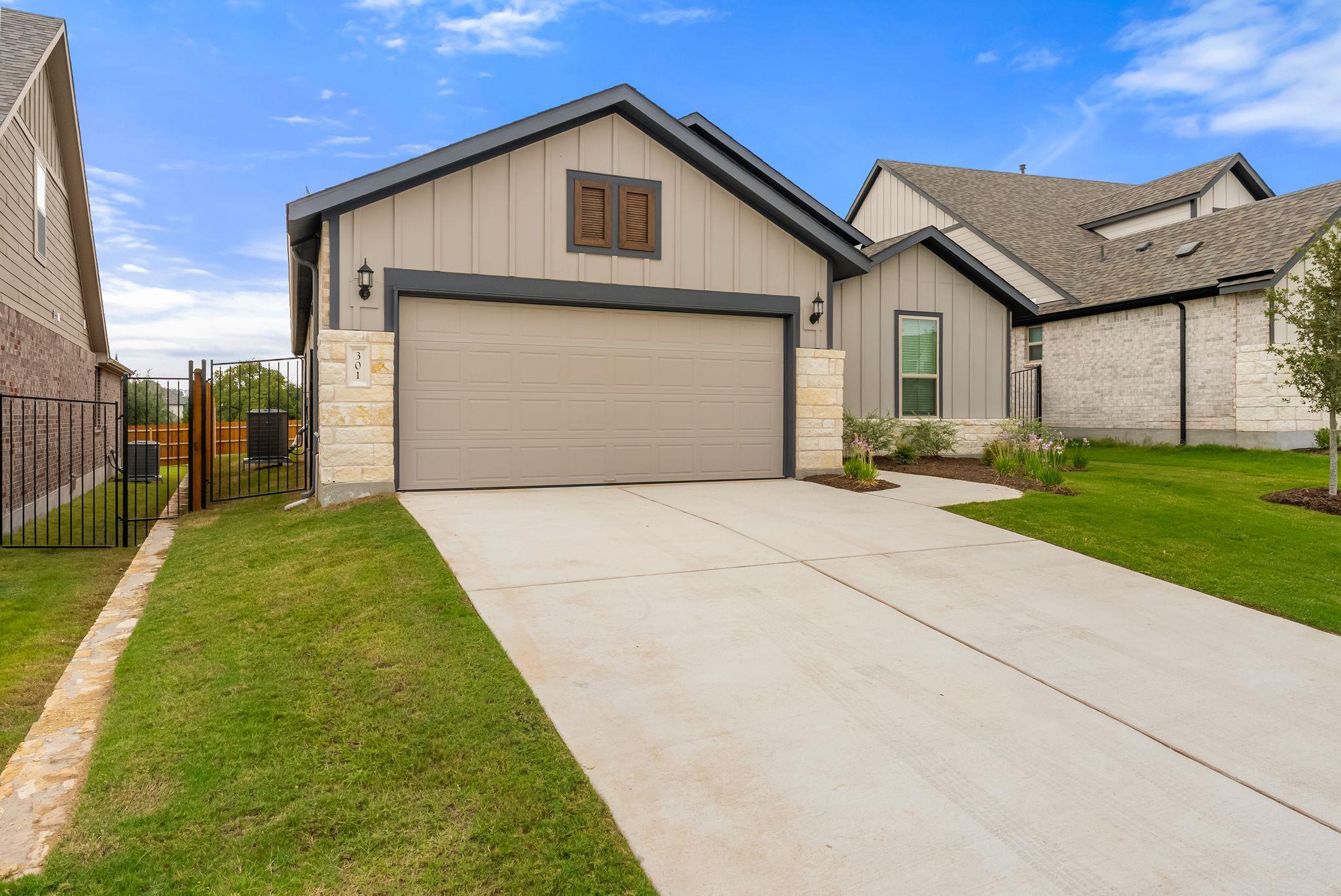 Home exterior with a two-car garage, broad driveway, and gated side yard.