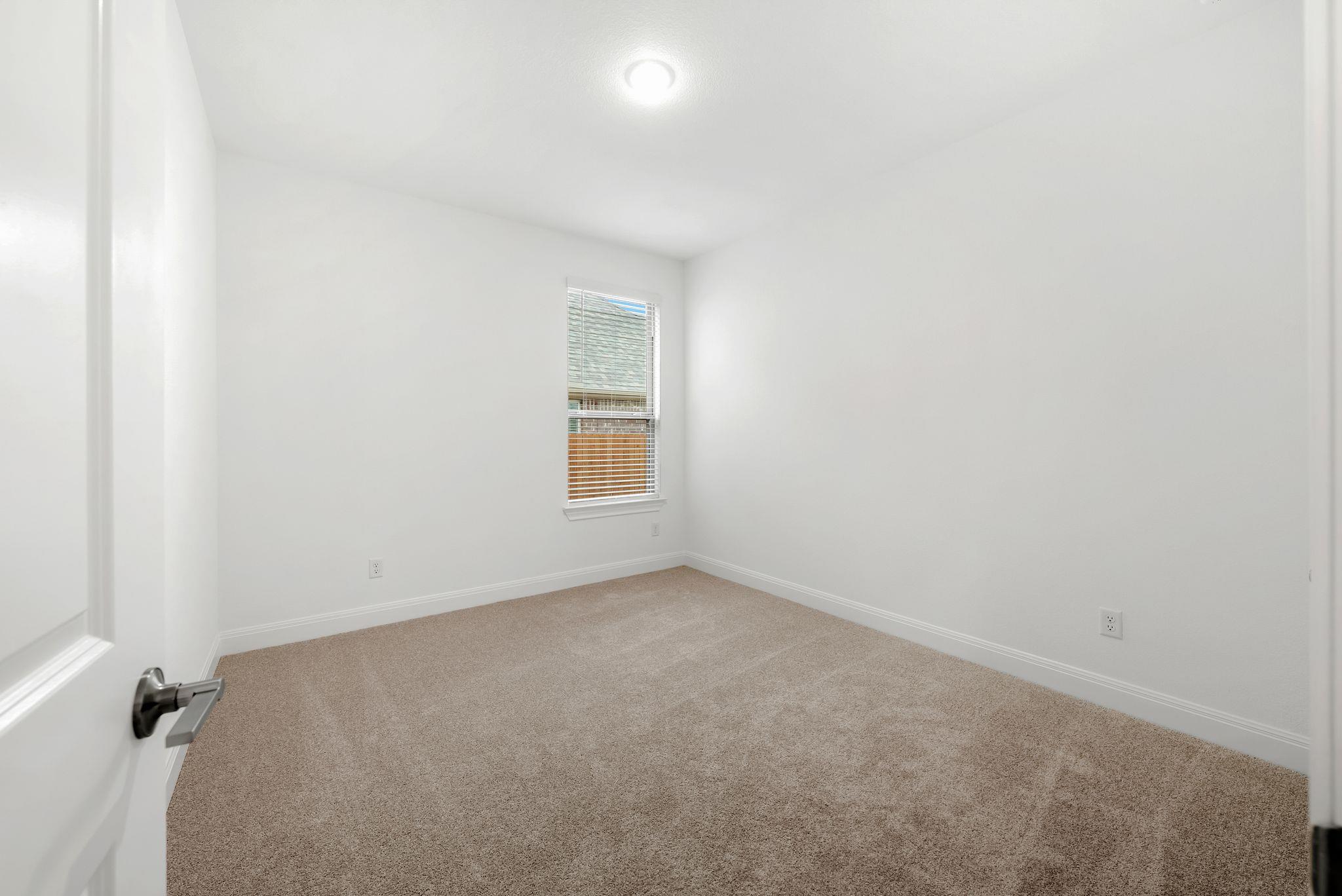 Empty bedroom with beige carpet, white walls, and a single window with blinds.