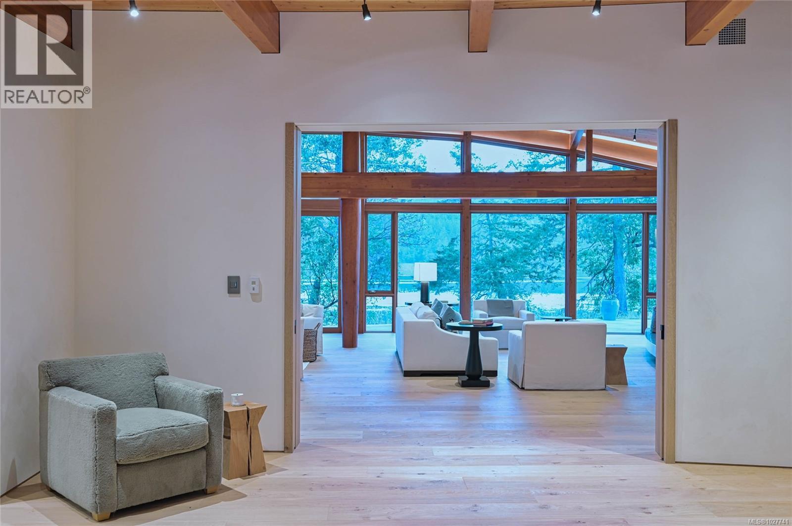 Living room with exposed timber beams and large windows overlooking the water.