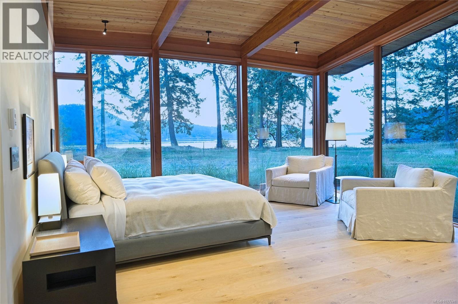 Furnished bedroom with floor-to-ceiling windows overlooking the water.